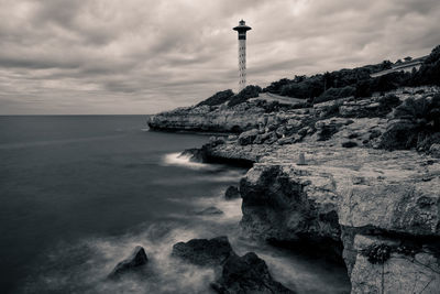 Lighthouse by sea against sky
