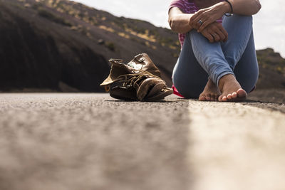 Low section of woman sitting on road