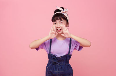 Portrait of woman standing against pink background