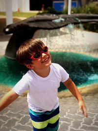 Portrait of happy boy wearing sunglasses on footpath 