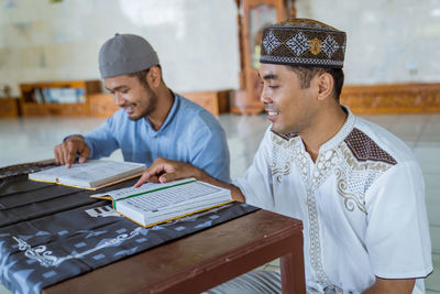 Smiling men reading koran at mosque