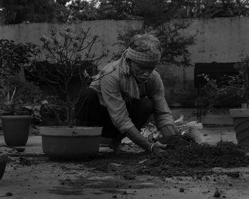 Gardener planting a plant by potted plants in yard