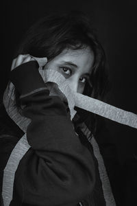 Portrait of young woman against black background