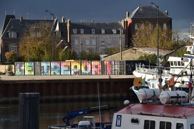 Boats moored at harbor by buildings in city