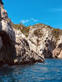 Rock formations by sea against blue sky