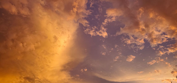 Low angle view of sunlight streaming through clouds during sunset