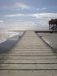 Boardwalk on beach against sky