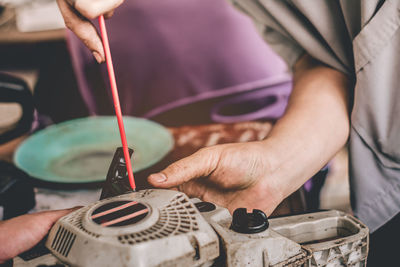 Close-up of mechanic repairing machinery on workbench in workshop