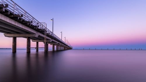 Bridge over sea against clear sky during sunset