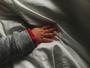 Cropped hand of baby girl on bed at home