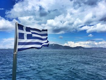 Greek flag at beach against sky