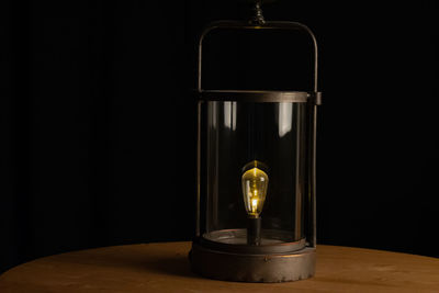 Close-up of illuminated lamp on table against black background