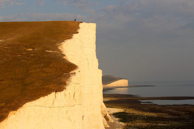 Rock formation on beach against sky