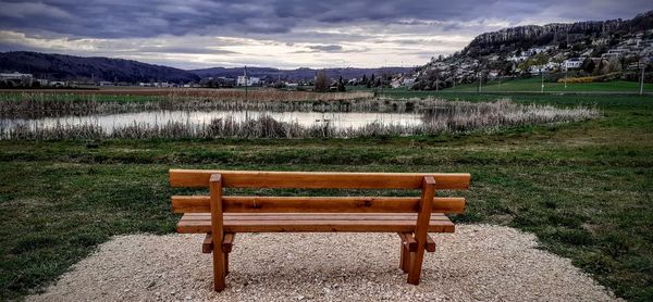 Empty bench on field against sky