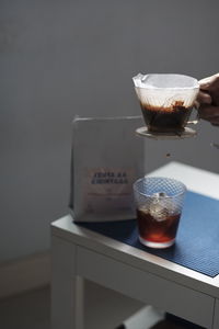 Close-up of hand holding drink on table