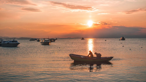 Sailboats in sea against sky during sunset