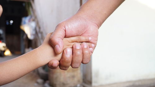 Cropped image of parent and child shaking hands