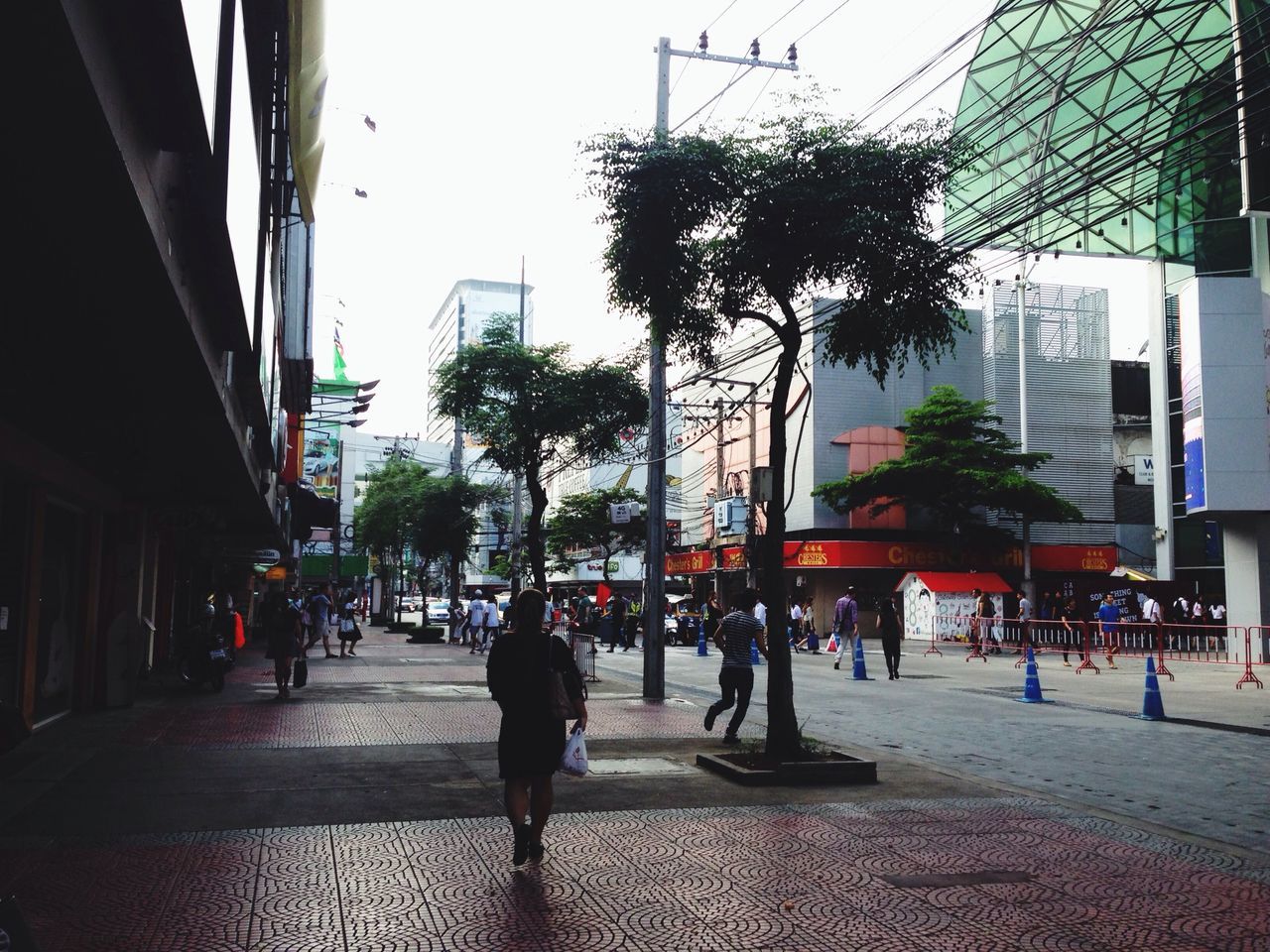 building exterior, architecture, built structure, city, street, city life, walking, men, city street, building, sidewalk, transportation, tree, person, incidental people, road, lifestyles, street light, clear sky