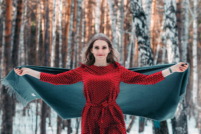 Young woman standing against trees