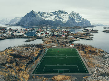 Aerial view of sea by snowcapped mountains against sky