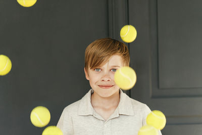 Smiling boy with falling tennis balls at home