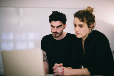 Business people discussing over laptop at desk in creative office