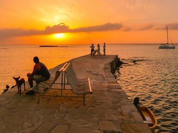 People at beach against orange sky