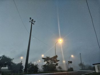 Low angle view of illuminated street lights against sky