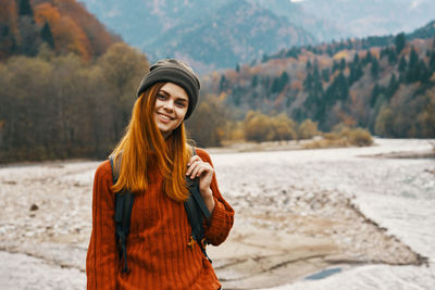 Portrait of smiling young woman standing on snow covered land