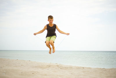 The boy on the beach is jumping rope. lifestyle themes. healthy . sports and training.