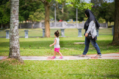 Full length of mother and daughter walking in park