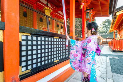 Side view of mid adult woman holding ribbon outside temple