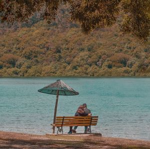 Rear view of man sitting on bench in water