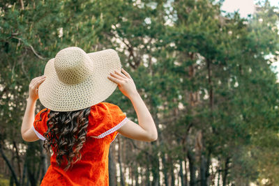 Rear view of woman wearing hat standing against trees