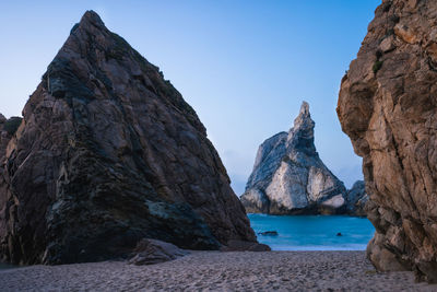 Panoramic view of rocks and sea against clear blue sky