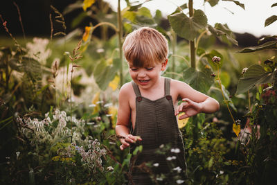 Close up of a smiling child walking in a field wearing dungarees