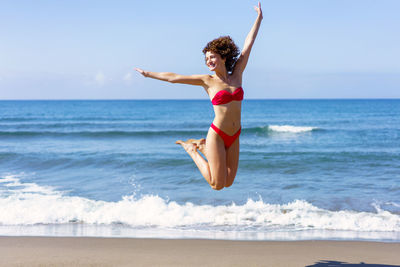 Full length of woman jumping at beach