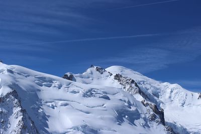 Scenic view of snowcapped mountains against blue sky