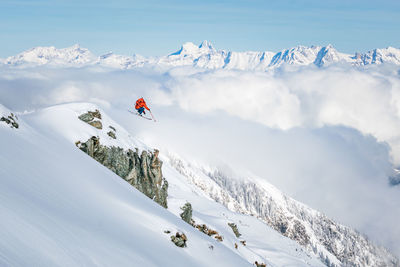 Man skiing on snowcapped mountain against sky