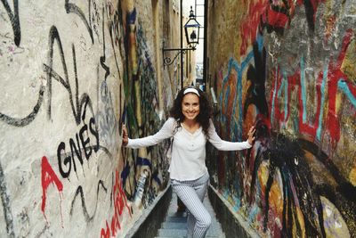 Portrait of teenage girl standing against graffiti wall