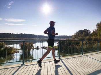 Side view of man on railing against lake