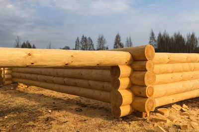 Stack of logs on field against sky