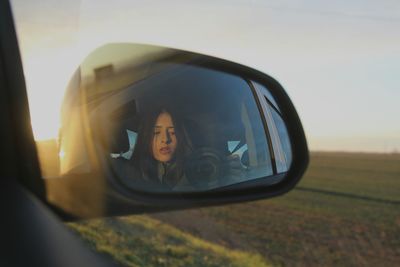 Reflection of woman on side-view mirror of car