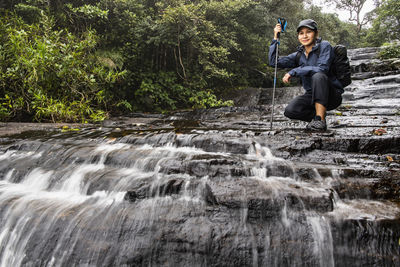 Woman exploring small waterfall in the mist of sri lankan highlands