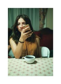 Close-up of woman holding coffee cup on table