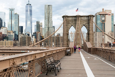 People on bridge against sky in city