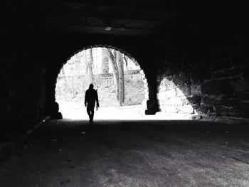 Silhouette man walking in tunnel