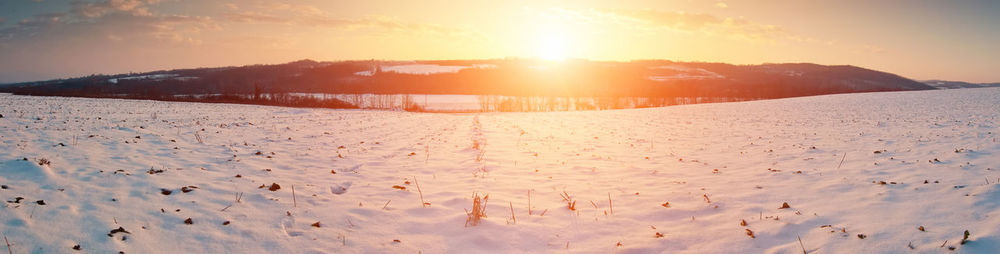 Scenic view of snow covered landscape against sky during sunset