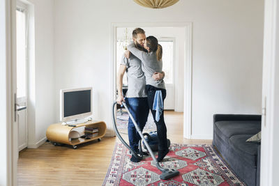 Young man holding woman standing at home