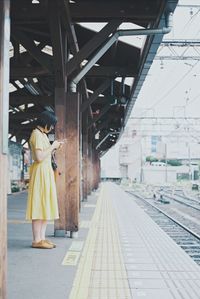 Side view of woman standing on railroad station platform